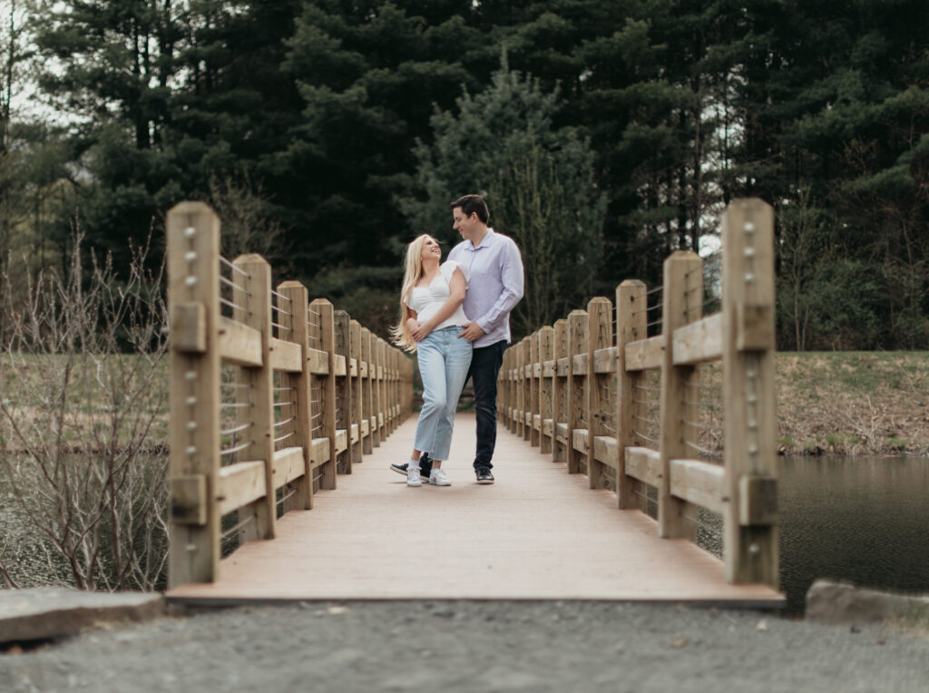 Engagement Session at Kenneth L. Wilson Campground. Woodstock, NY. couple walking on bridge. beautiful landscape, grooms picks up bride. couple locked in embrace.