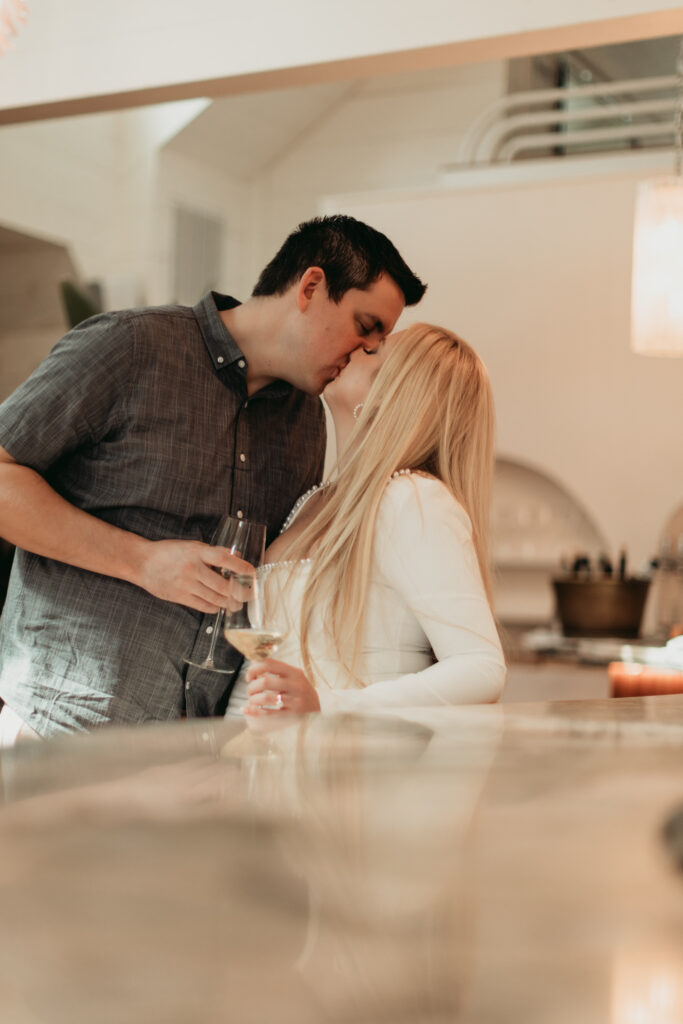 candid shot of couple sharing a kiss and drinks at the bar