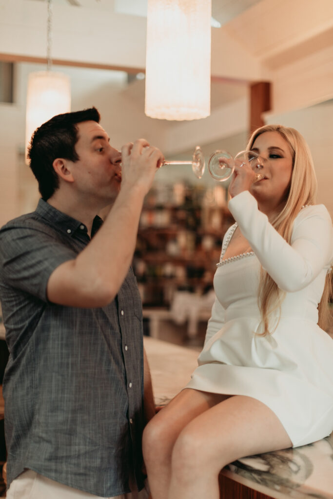 Engagement Session at Goodnight Restaurant toasting and drinking wine at the bar. sharing a kiss. modern moody photography