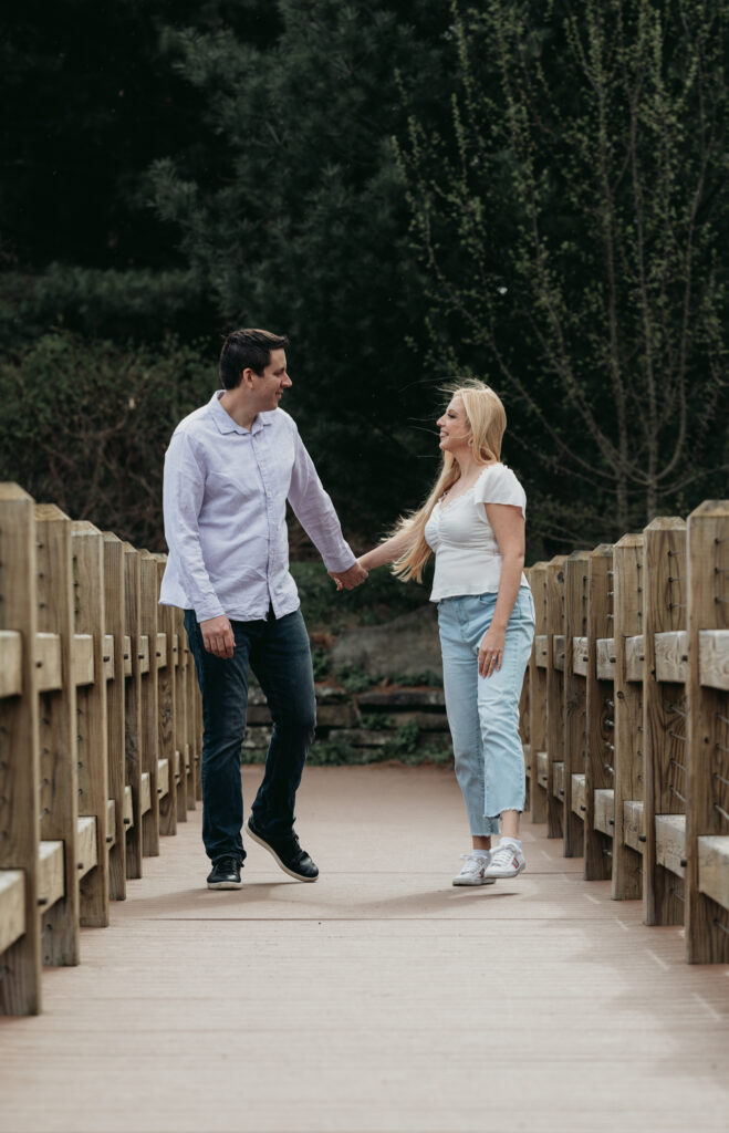 Engagement Session at Kenneth L. Wilson Campground. Woodstock, NY. couple walking on bridge. beautiful landscape, couple smiling at each other.