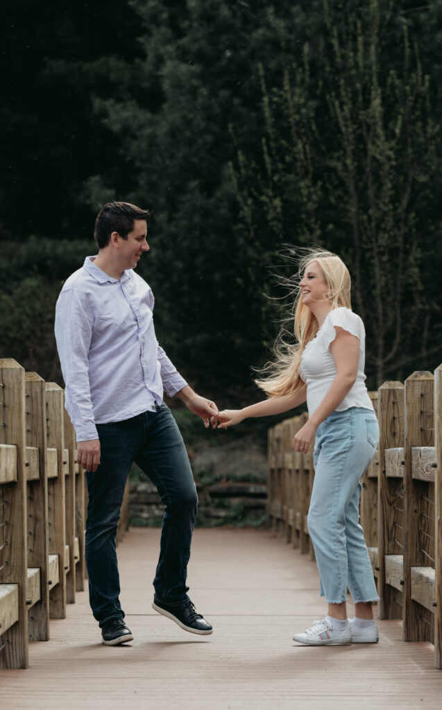 Engagement Session at Kenneth L. Wilson Campground. Woodstock, NY. couple walking on bridge. beautiful landscape, couple smiling at each other.