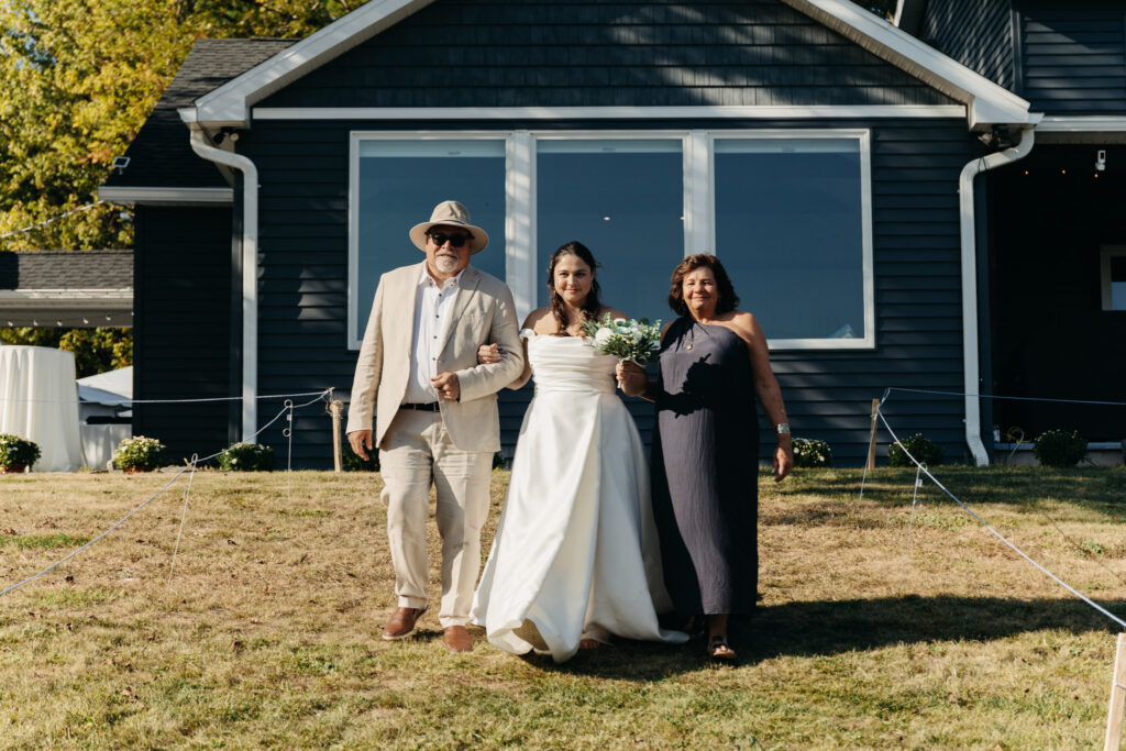 bride walking down the aisle with her parents during the wedding ceremony