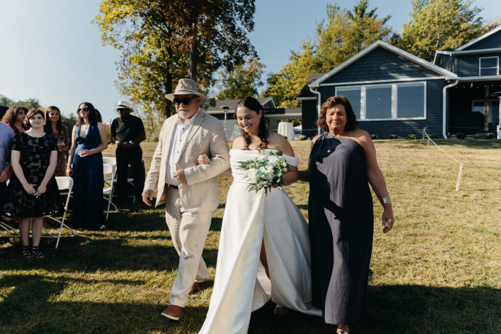 bride walking down the aisle with her parents during the wedding ceremony