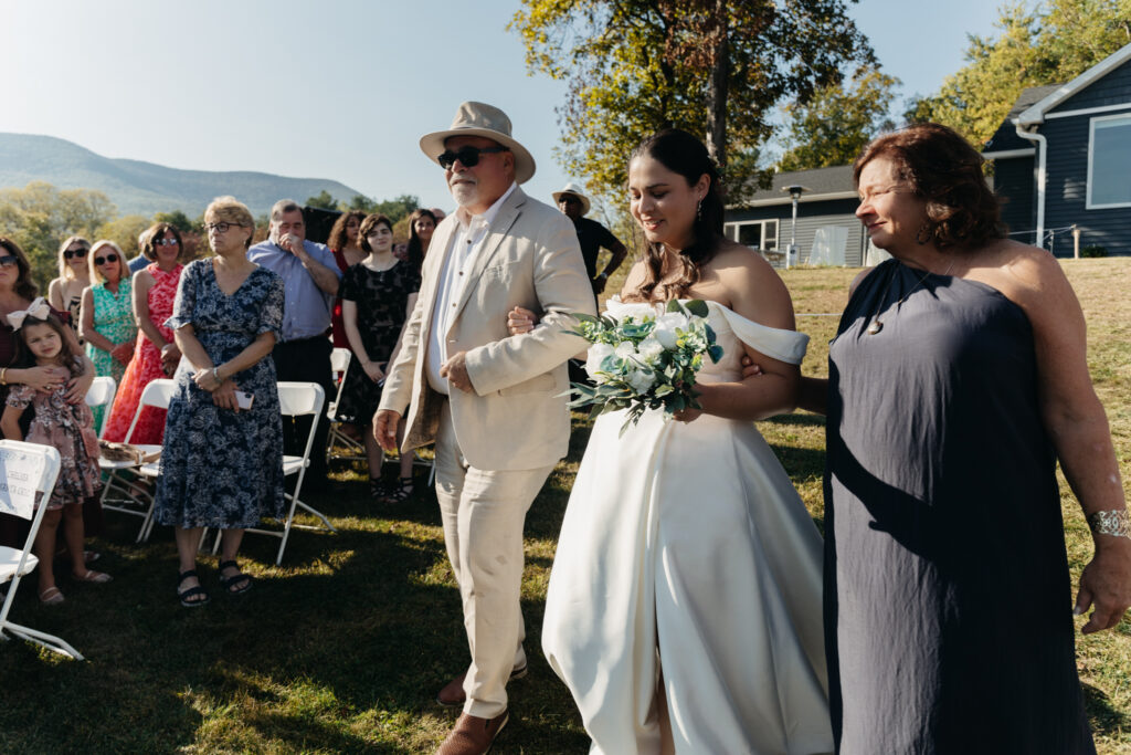 bride walking down the aisle with her parents during the wedding ceremony