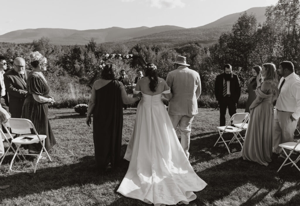 bride walking down the aisle with her parents during the wedding ceremony black and white photo round top new york