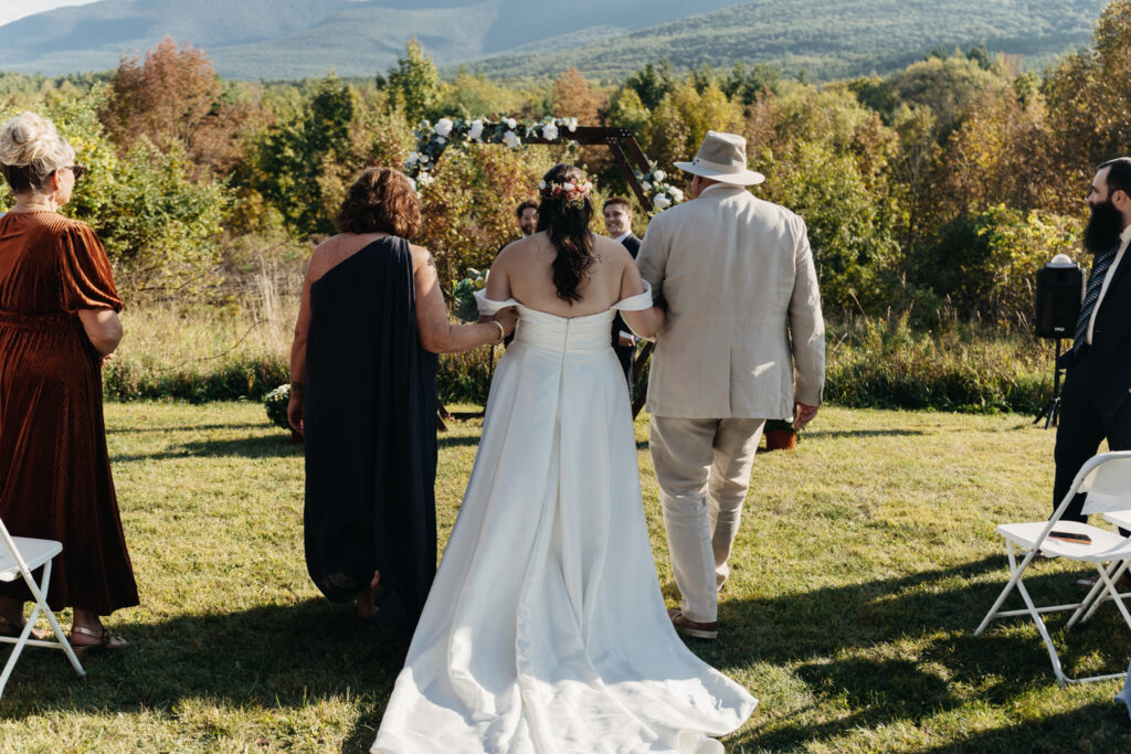 bride walking down the aisle with her parents during the wedding ceremony round top new york