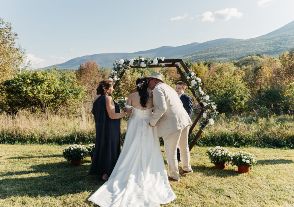 father of bride kisses her as he leaves her at the altar