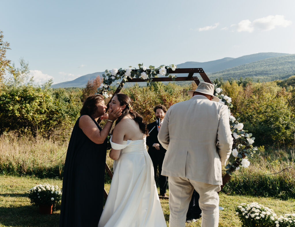 mother of bride giving kiss to the bride at the altar.