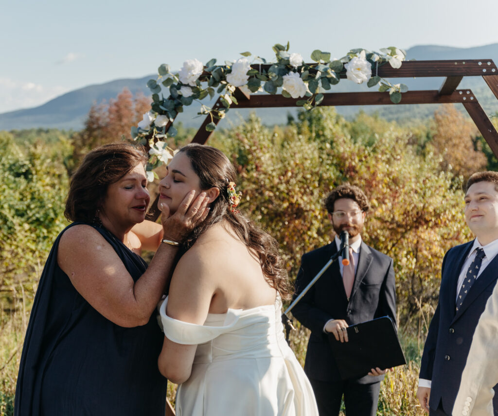 mother of bride giving kiss to the bride at the altar.